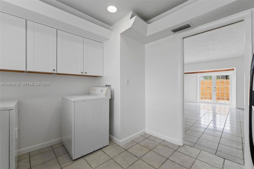 Utility area featuring white shaker-style cabinetry, recessed lighting, and tile flooring
