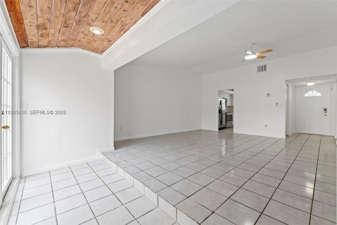 Open interior space featuring a wood-plank ceiling treatment, ceramic tile flooring, recessed lighting, and white paneled entry door