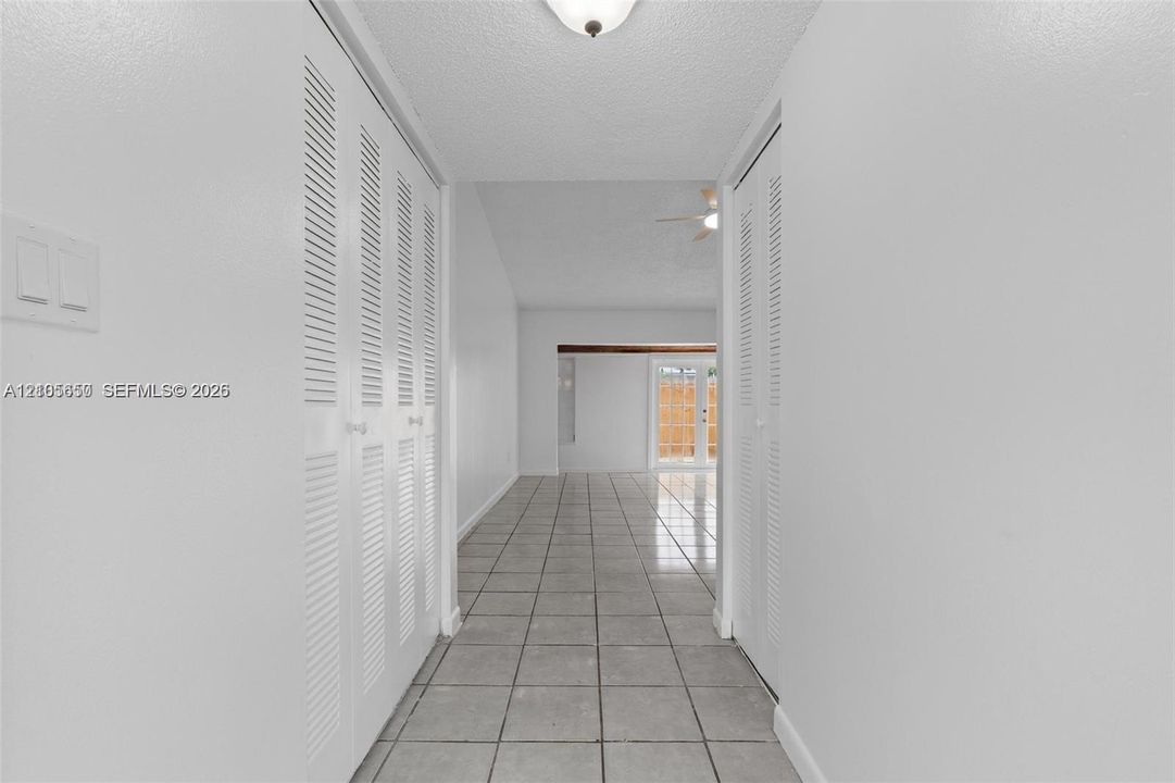 Neutral tile flooring, dual sets of bi-fold louvered closet doors, and a vaulted ceiling