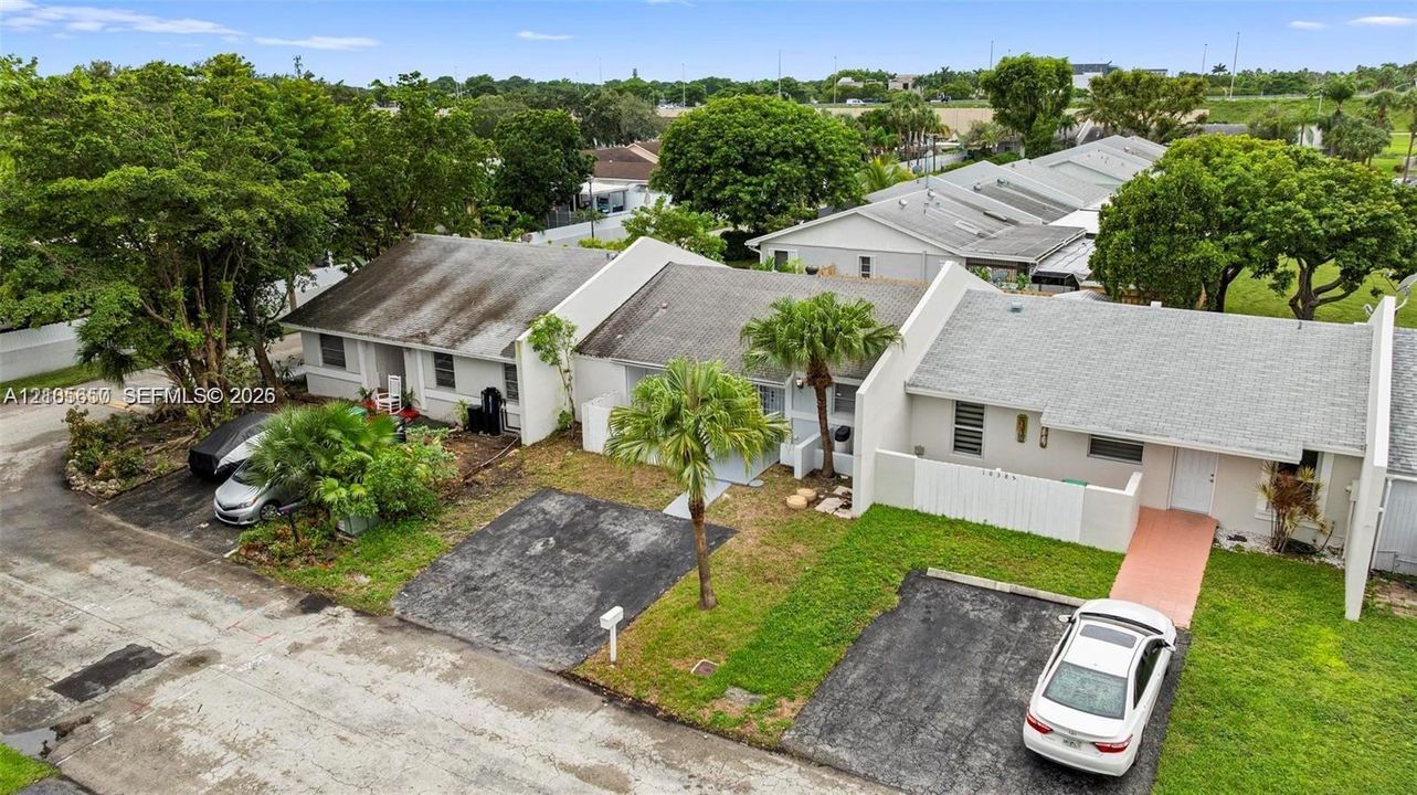 Single-story residential structures featuring light-toned exteriors, shingle roofing, private driveways, and mature landscaping