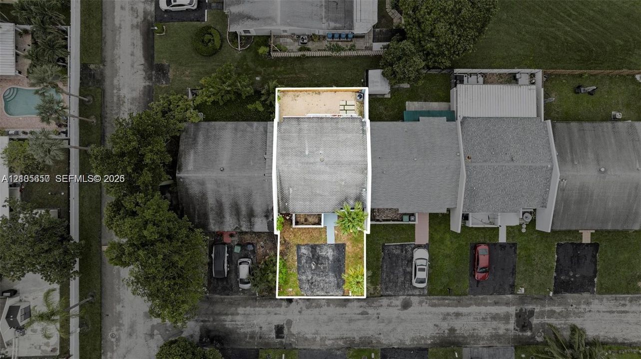 Aerial perspective of property featuring an asphalt driveway, concrete rear patio, and mature landscaping