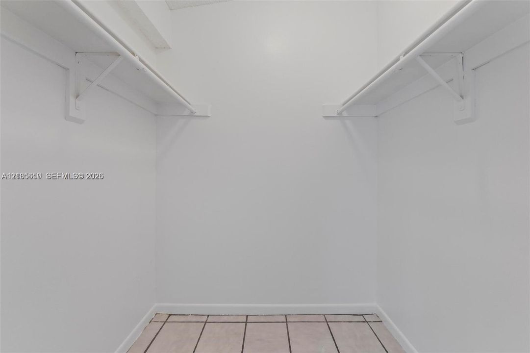 Storage space featuring dual-sided shelving and tile flooring