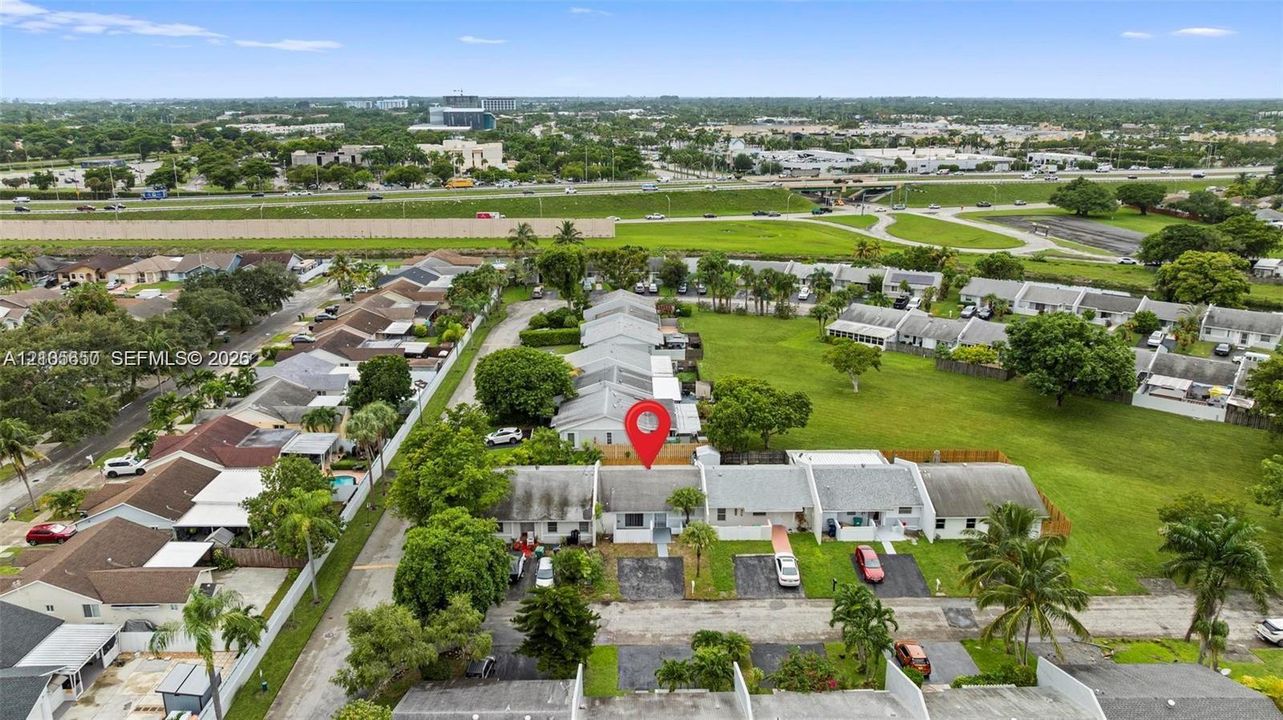 Aerial perspective of a single-story residence featuring an asphalt shingle roof, paved driveway, and mature landscaping