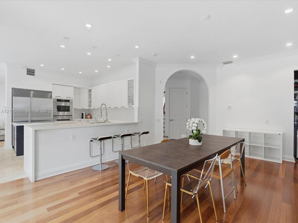 Open-concept interior featuring wood-finish flooring, recessed lighting, and a kitchen equipped with stainless steel appliances, crisp white cabinetry, and a countertop island