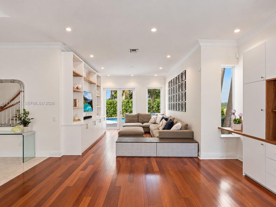 Living area featuring wood-finish flooring, recessed lighting, floor-to-ceiling custom built-in cabinetry, and French doors