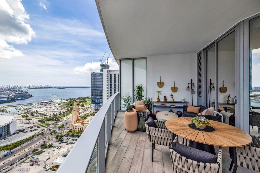 Expansive covered balcony featuring wood-finish flooring and a tempered glass railing