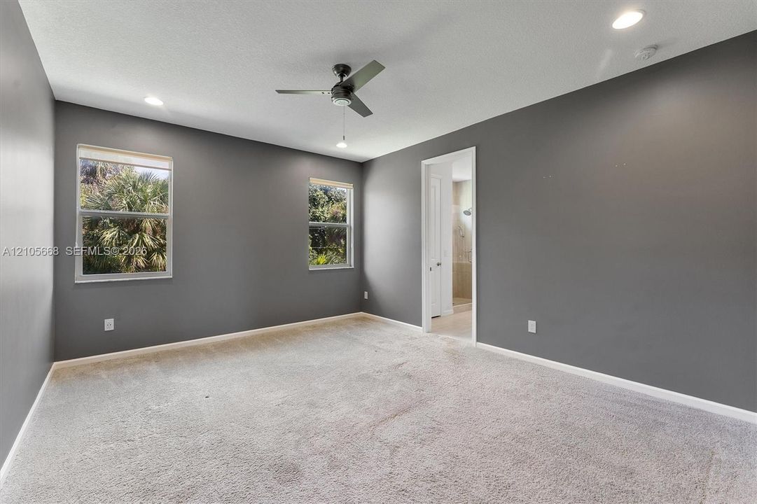 Neutral-toned interior featuring wall-to-wall carpeting, recessed lighting, a modern ceiling fan, and dual windows