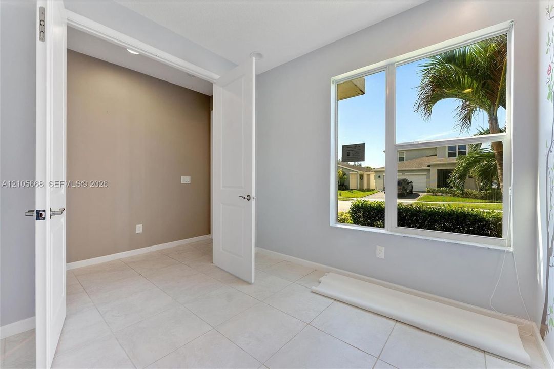Light-filled room featuring large-format tile flooring, neutral wall tones, multi-panel interior doors, and a picture window