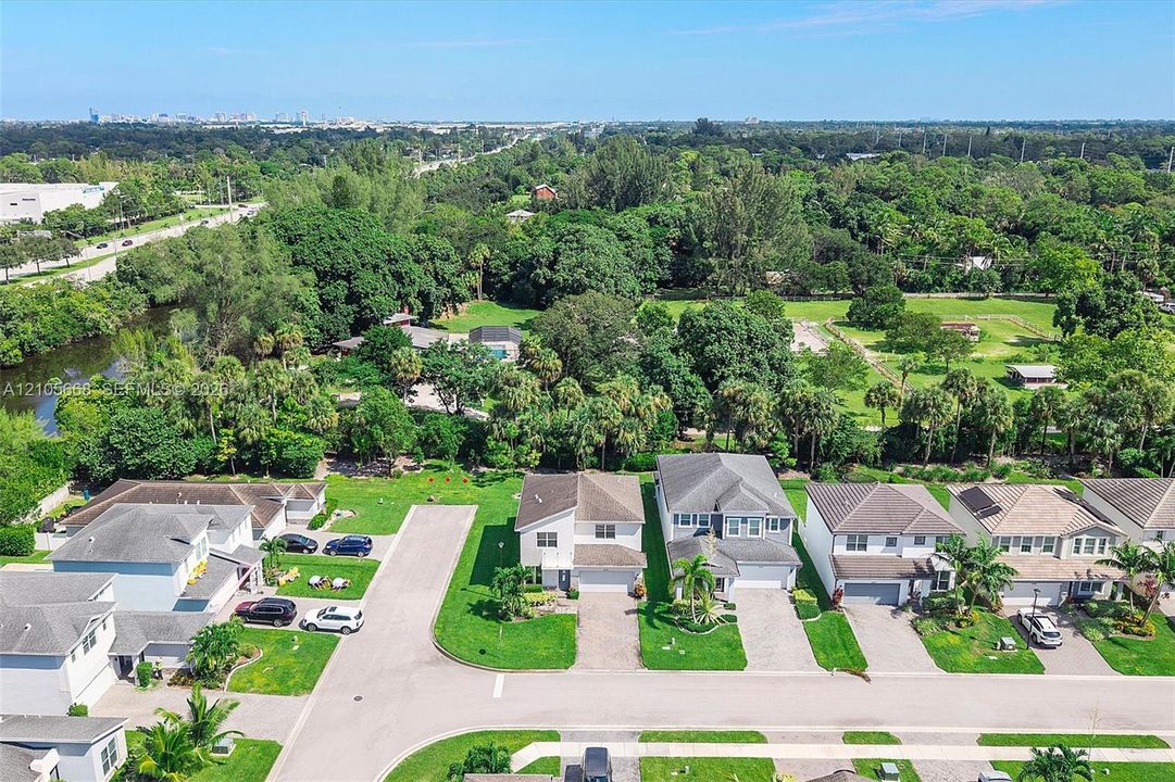 Aerial perspective of a suburban neighborhood featuring multi-story dwellings, paver driveways, attached garages, and extensive mature tree canopy