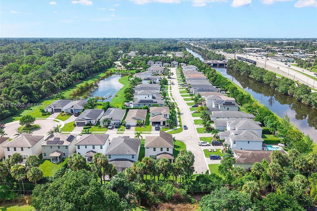 Aerial perspective featuring a residential subdivision with paved roadways, suburban single-family housing, integrated retention ponds, and established perimeter vegetation
