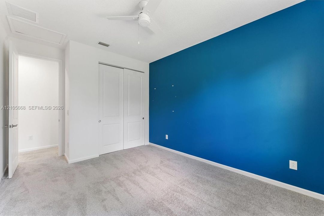 Room featuring neutral wall-to-wall carpeting, a dual-panel closet, and a ceiling fan
