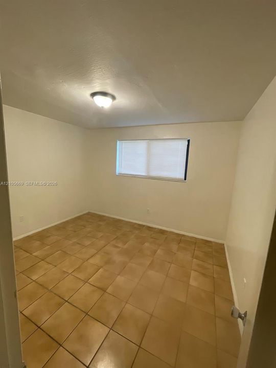 Neutral-toned ceramic tile flooring, clean painted walls, flush-mount ceiling light fixture, and a horizontally sliding window