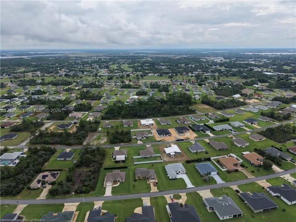 Aerial perspective of a residential neighborhood featuring established grid streets, mature trees, manicured lawns, and clusters of single-story residences