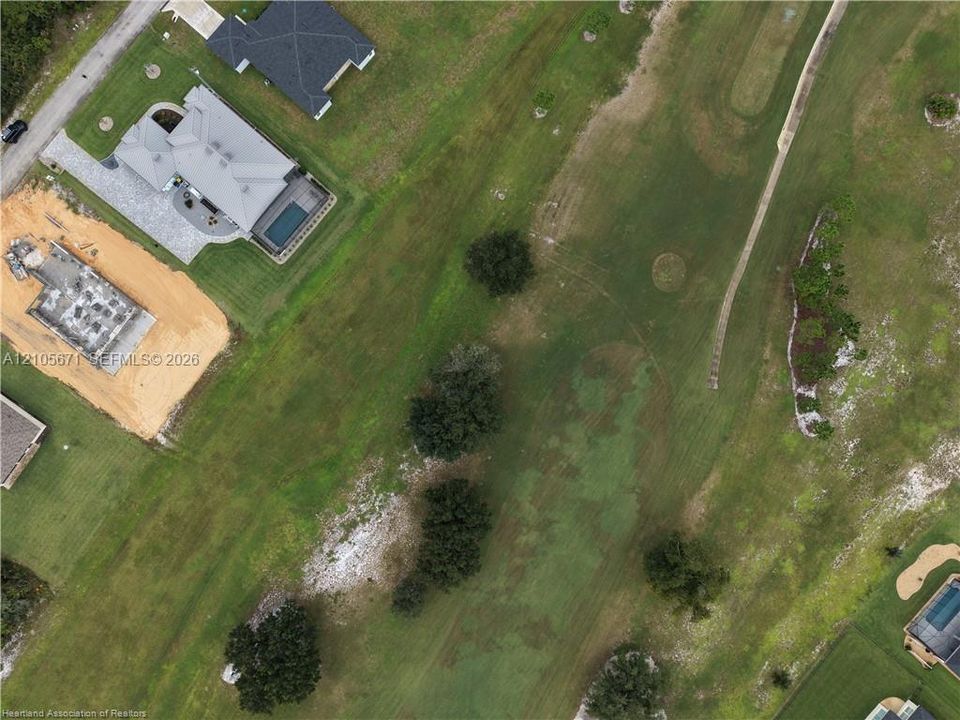 Aerial perspective featuring an expansive lot with mature trees and direct access to a paved cart path