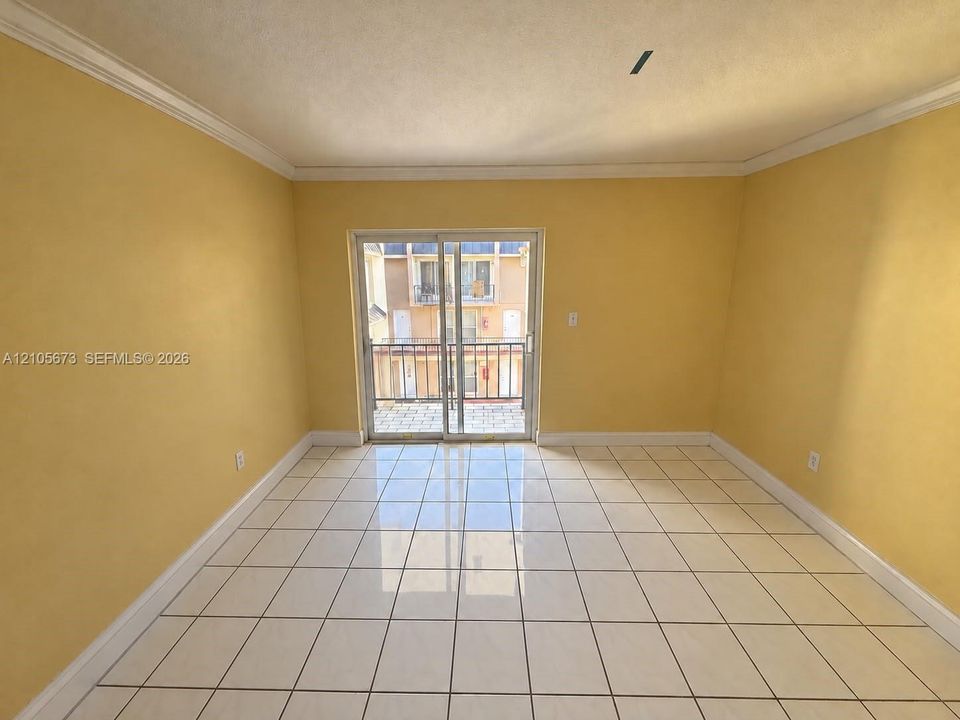 Ceramic tile flooring, crown molding, and glass sliding doors opening to a private balcony