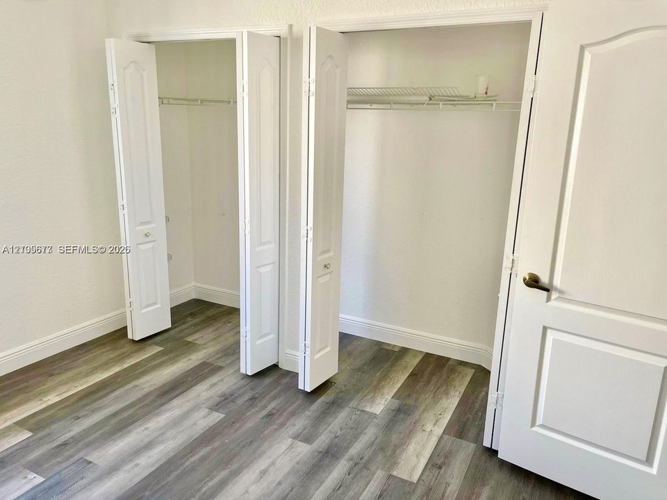 Dual reach-in closets featuring bi-fold doors, white interior finishes, wire shelving, and wood-finish flooring