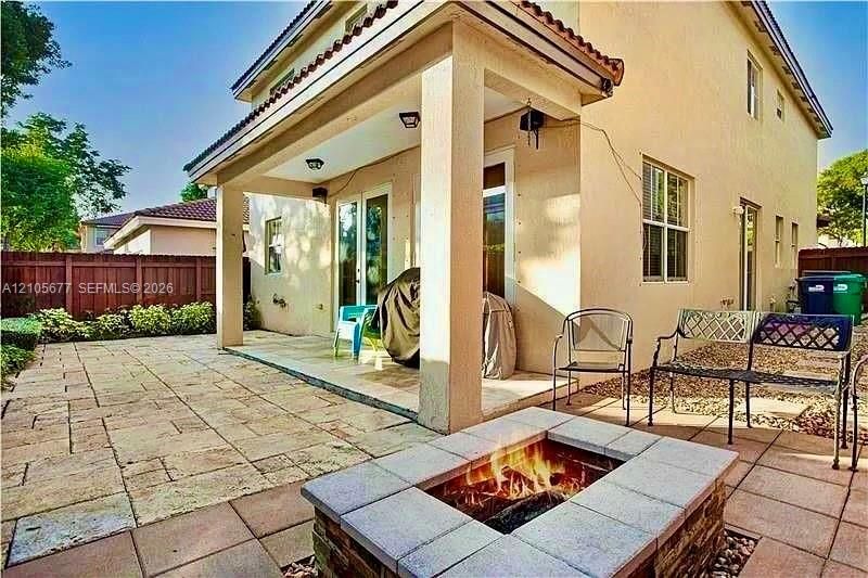 Covered patio with recessed lighting, stone-tiled flooring, and a built-in stone-surround fire pit