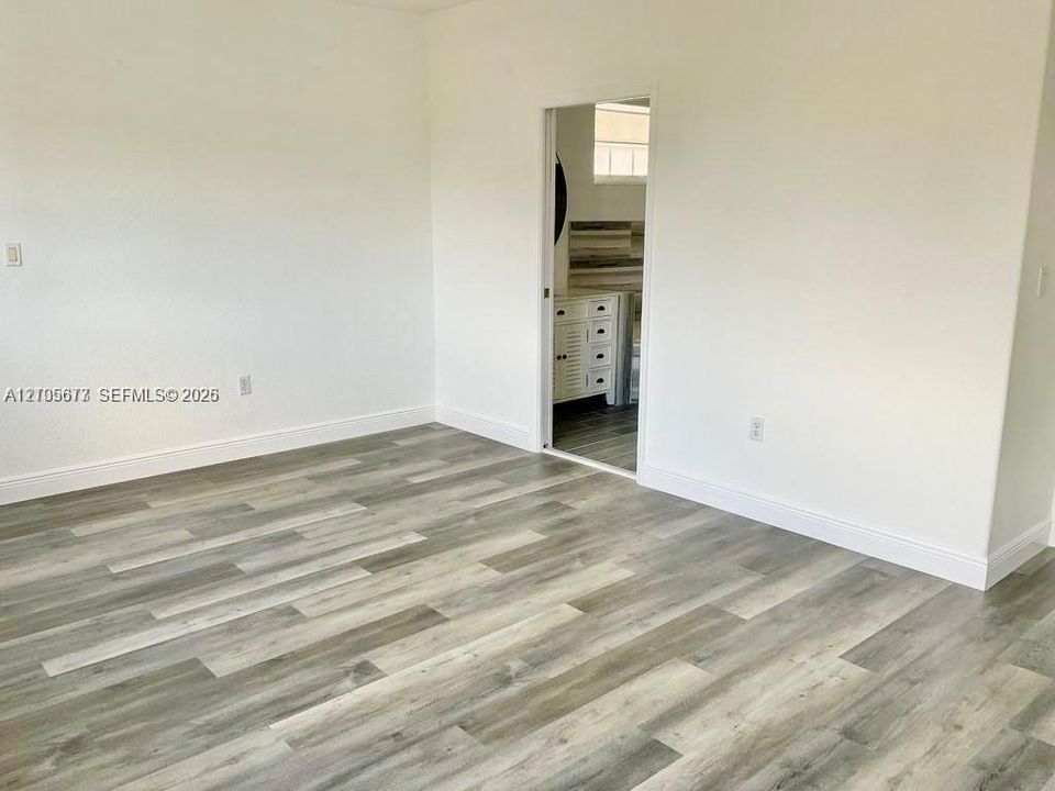 Interior space featuring wood-finish flooring, smooth-finish walls, and a white vanity cabinet with drawers