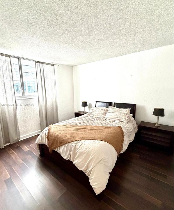 Dark-tone wood-finish flooring and single-pane window with metal frame