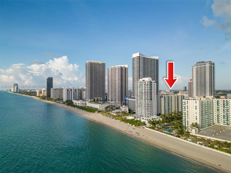 High-rise residential building situated along the coastal shoreline featuring direct proximity to the ocean and sandy beach
