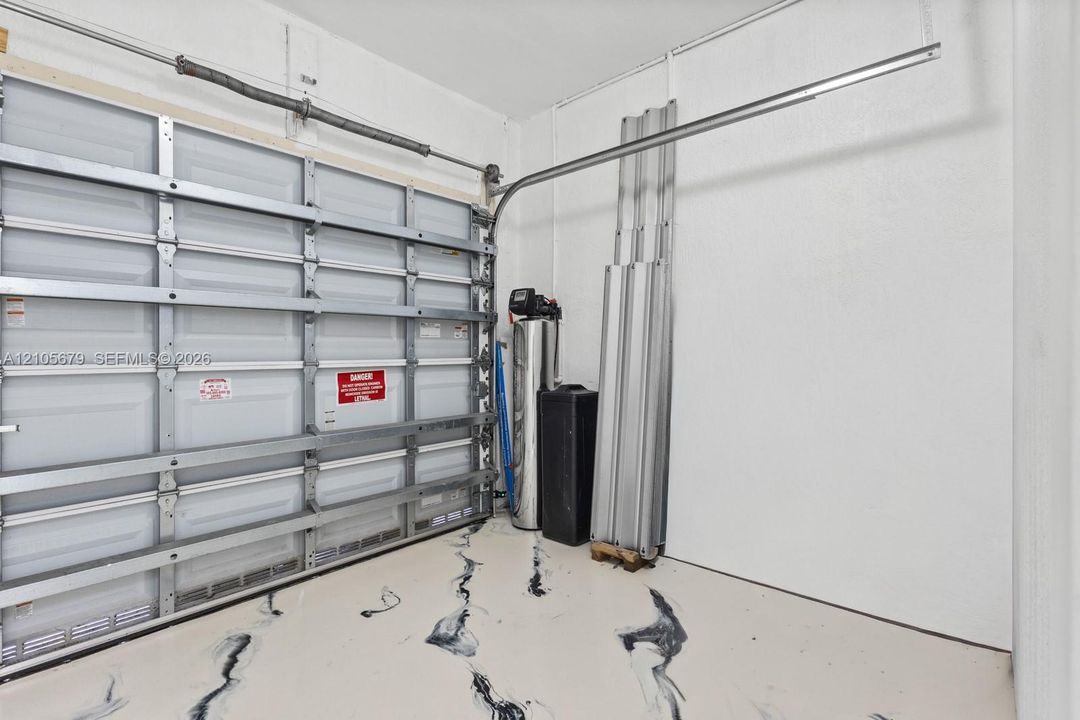 Finished garage interior featuring a metal sectional door, epoxy-coated floor with decorative marbling, and an integrated water filtration system