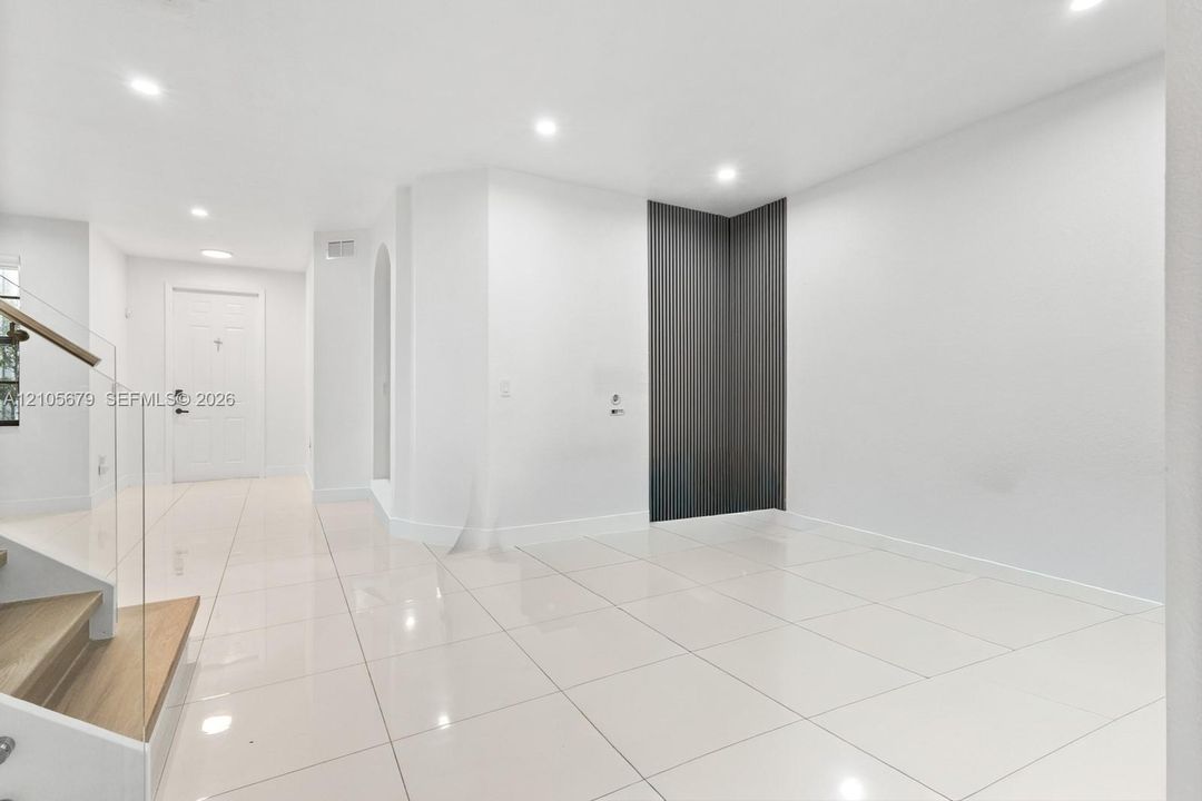 Interior space featuring large-format tile flooring, recessed lighting, and a modern glass-panel staircase railing