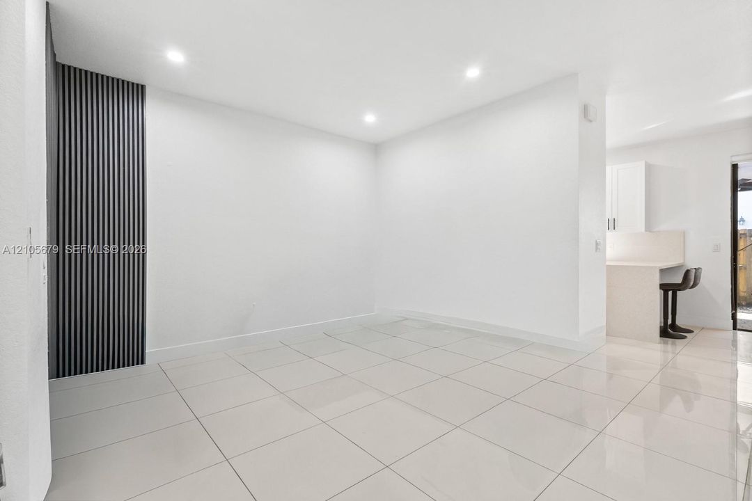 Large-format tile flooring, vertical slat accent wall, and recessed lighting