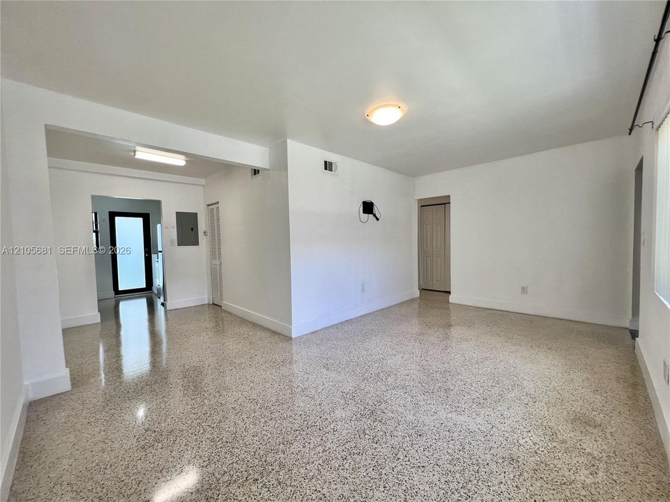 Open interior space featuring terrazzo flooring, neutral wall finishes, flush-mount ceiling lighting, and a bi-fold closet door