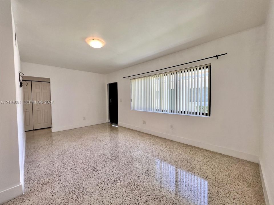 Terrazzo flooring, large window with vertical blinds, and bi-fold closet doors