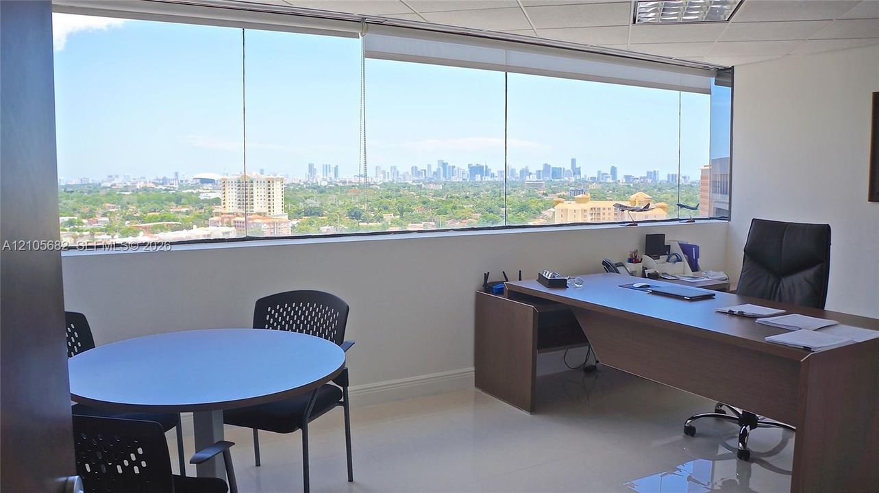 Floor-to-ceiling windows featuring panoramic urban skyline scenery, minimalist white walls, and polished light-toned flooring