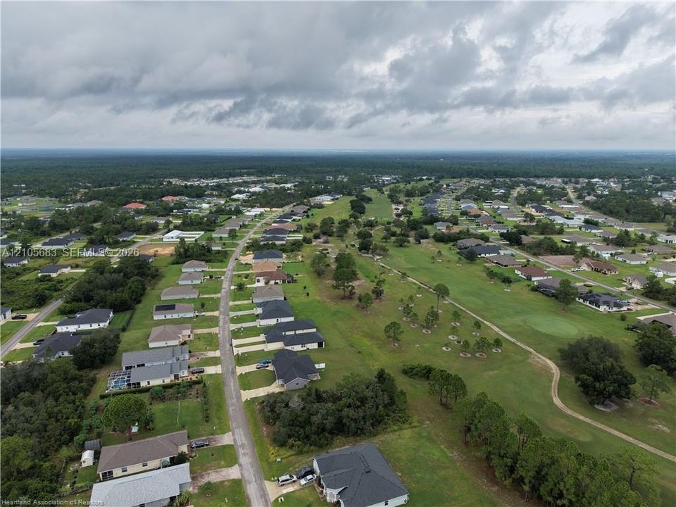 Aerial perspective of residential properties featuring paved streets, established landscaping, and proximity to expansive open green spaces