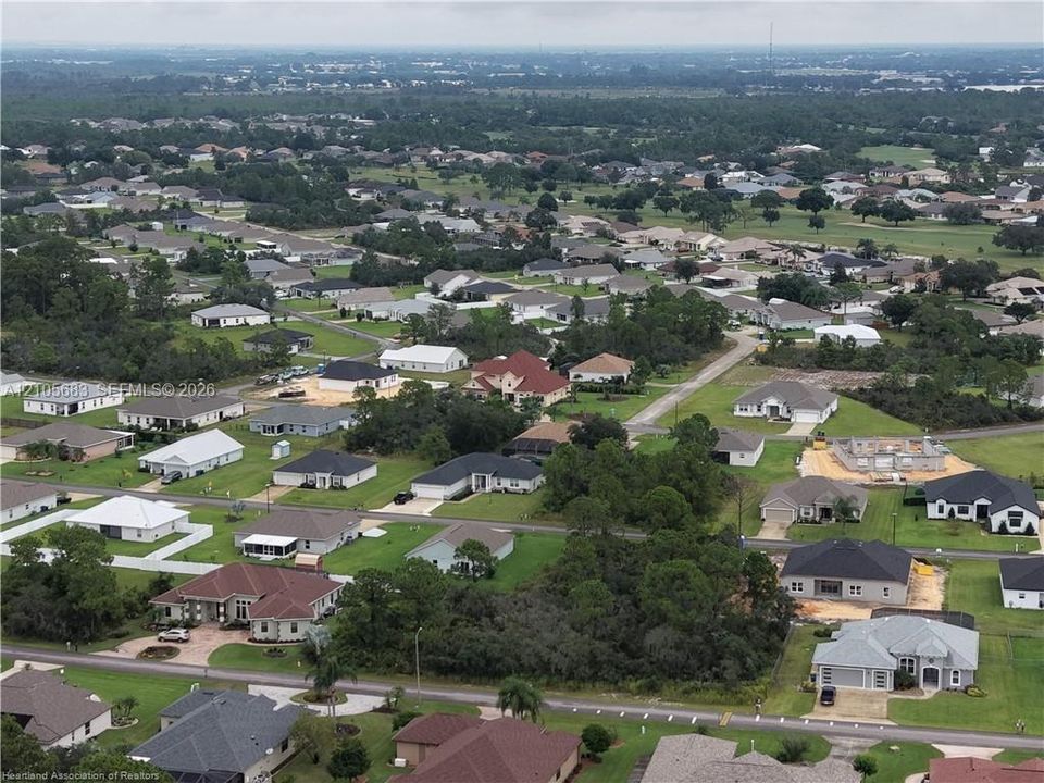 Aerial perspective of a suburban neighborhood featuring paved streets, established landscaping, mature trees, and varying residential architectural styles