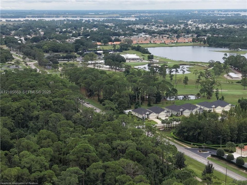 Aerial perspective featuring extensive wooded areas, expansive golf course grounds, natural water bodies, and integrated residential neighborhood clusters