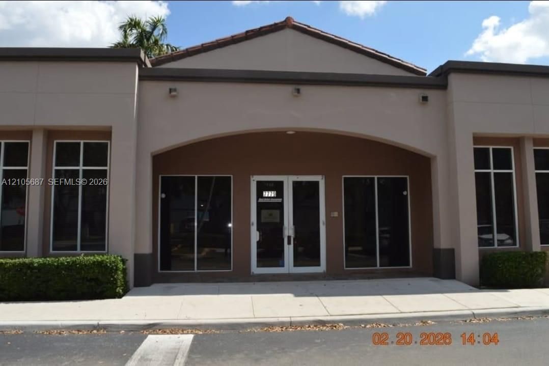 Stucco exterior featuring an arched entryway, double-glass front doors, and large grid-pattern windows