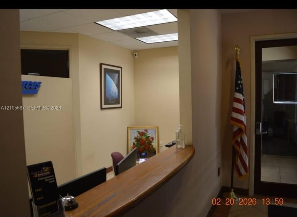 Office space featuring a solid wood reception counter, drop ceiling with recessed lighting, and glass-paneled entry door