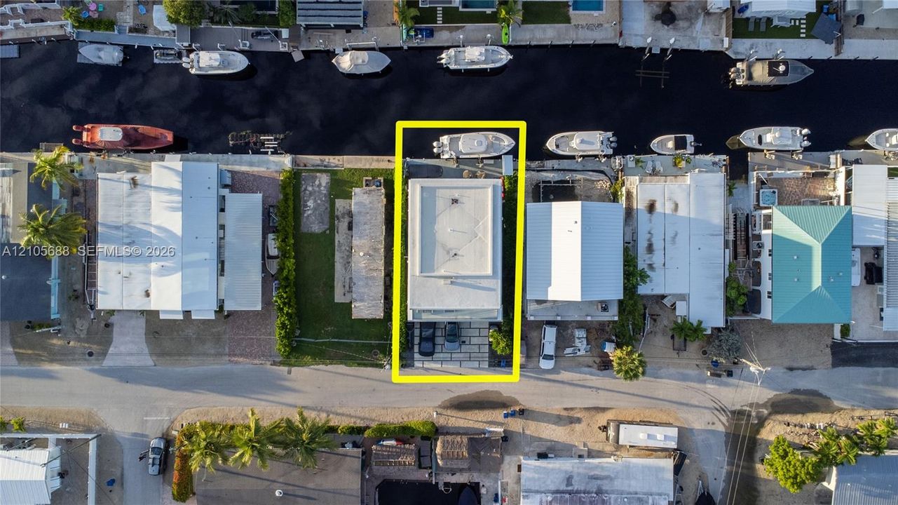 Aerial perspective of a waterfront property featuring a paved driveway, private boat dock, and direct canal access