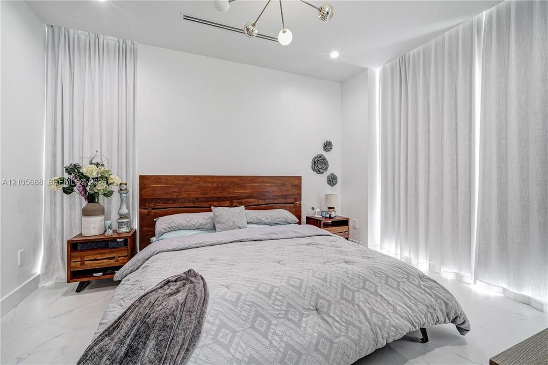 Room featuring large-format light-toned tile flooring, floor-to-ceiling drapery, and a modern multi-bulb chandelier