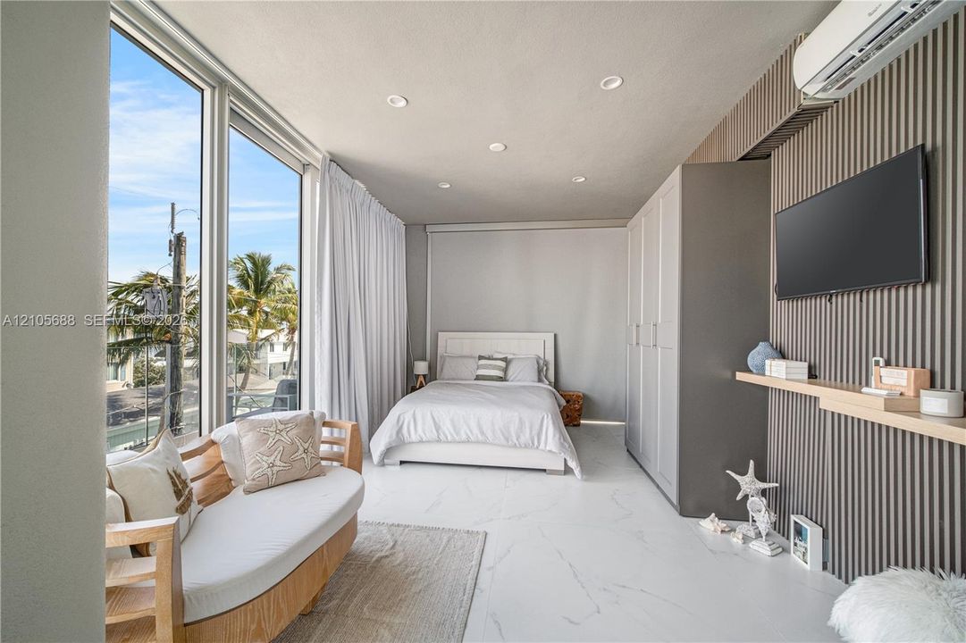 Floor-to-ceiling windows, polished stone-finish flooring, vertical slat accent wall, recessed lighting, and a built-in floor-to-ceiling wardrobe
