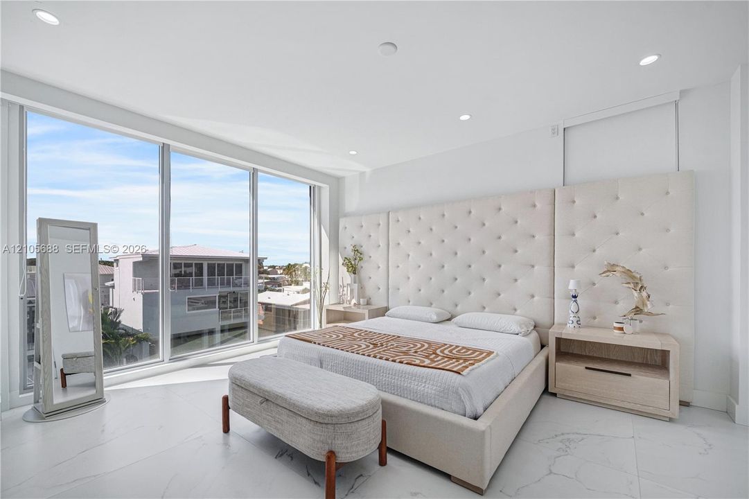 Floor-to-ceiling windows, custom tufted wall paneling, and polished stone tile flooring