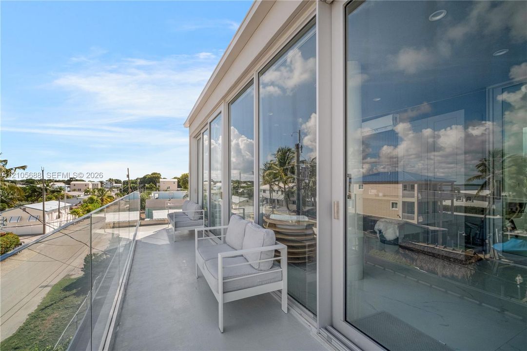 Expansive balcony featuring floor-to-ceiling glass wall panels, a seamless glass railing, recessed ceiling lighting, and smooth-finish flooring