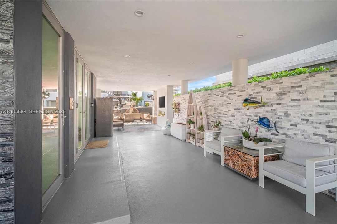Covered patio featuring a stacked stone accent wall, recessed lighting, concrete flooring, and full-height glass door panels