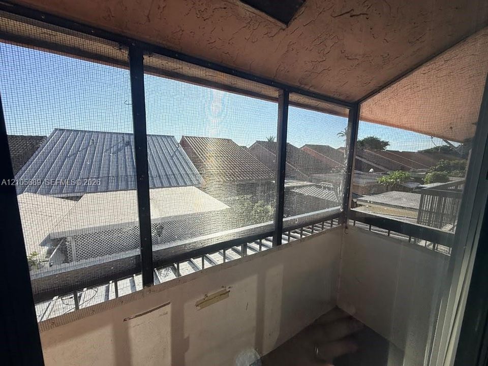 Enclosed balcony featuring black metal framing, screen panels, and a textured ceiling