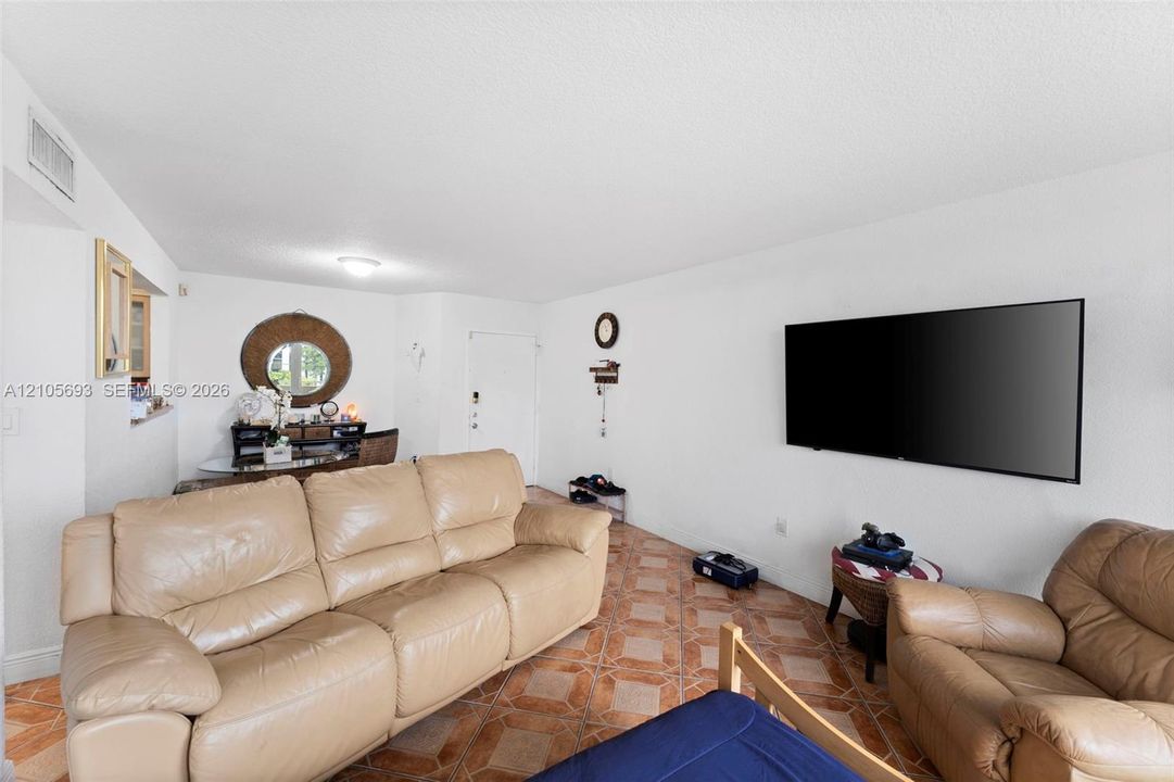 Open-concept living space featuring patterned tile flooring, a pass-through wall opening, and a flush-mount ceiling light fixture