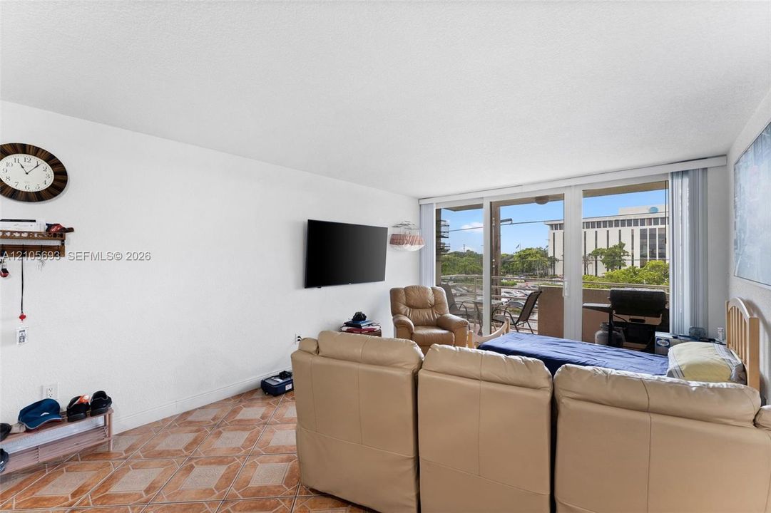 Living space featuring large-format decorative ceramic tile flooring, expansive sliding glass doors, and a private balcony