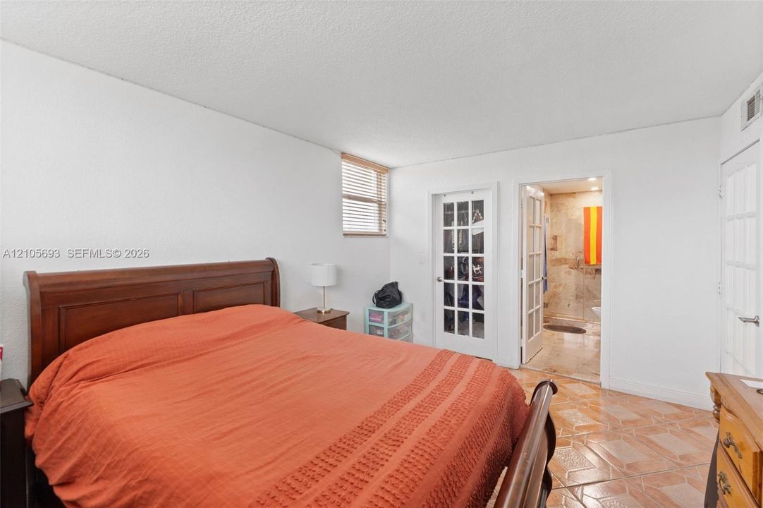 Room featuring ceramic tile flooring, horizontal blinds, and two sets of white French doors