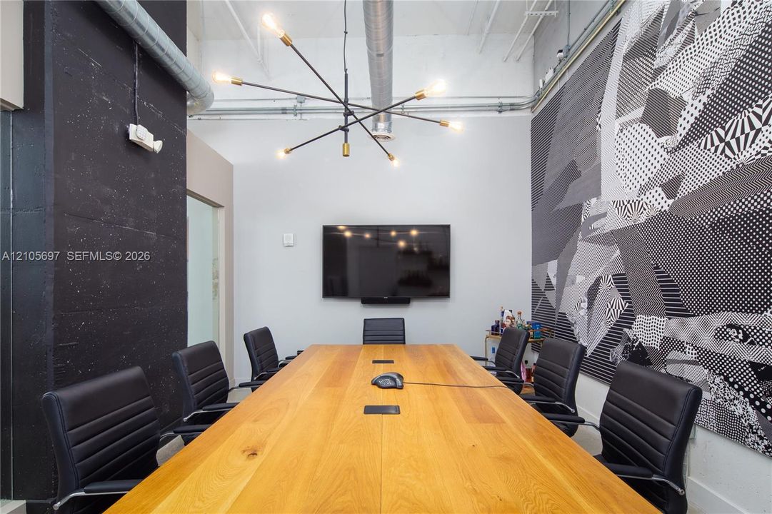 Industrial-style interior featuring high ceilings with exposed ductwork, a multi-arm sputnik-style light fixture, and a textured black architectural column