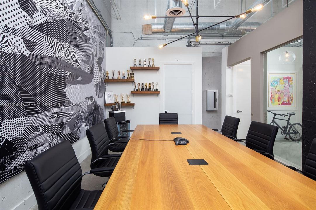 Industrial-style space featuring exposed ductwork, high ceilings, built-in wooden wall shelving, a large multi-arm chandelier, and glass partition walling