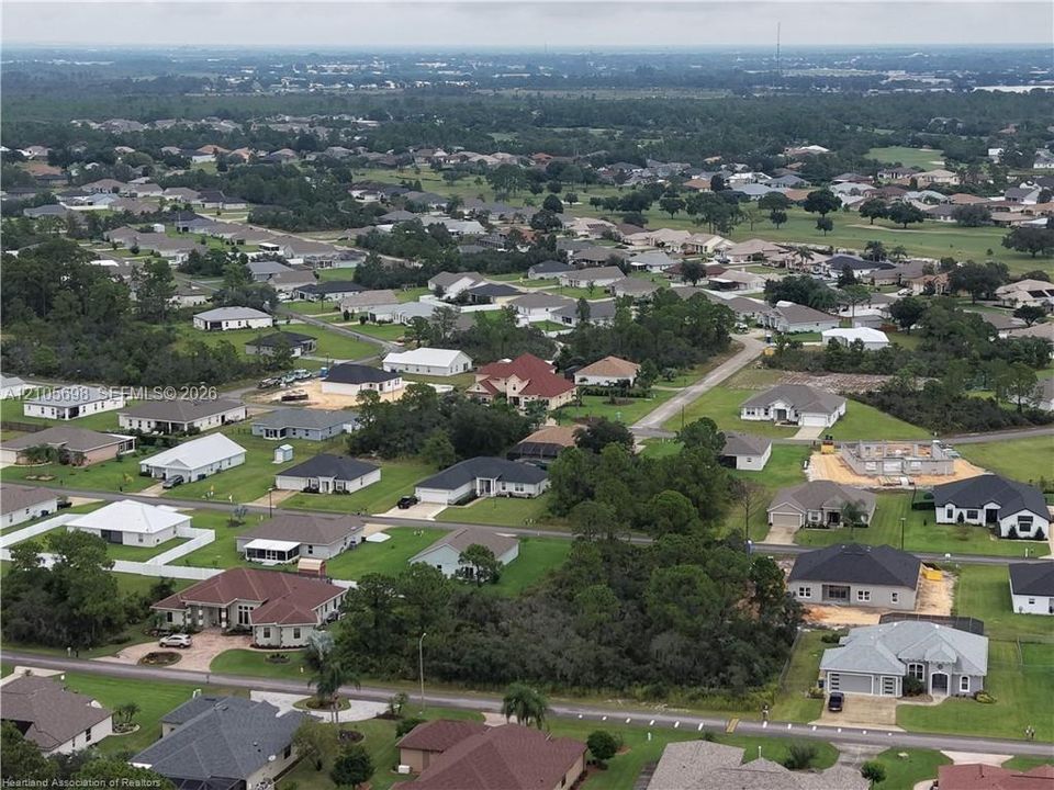 Aerial perspective of a suburban neighborhood featuring paved streets, established landscaping, mature trees, and varying residential architectural styles