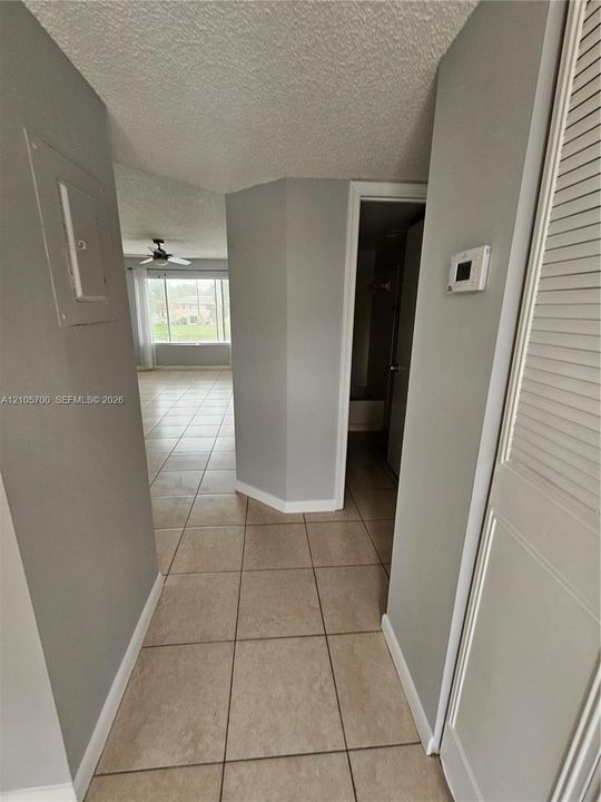 Ceramic tile flooring, louvered bi-fold closet doors, and wall-mounted digital thermostat