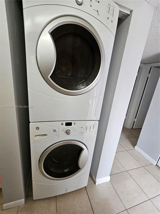 Stacked white front-load washer and dryer unit with metallic trim